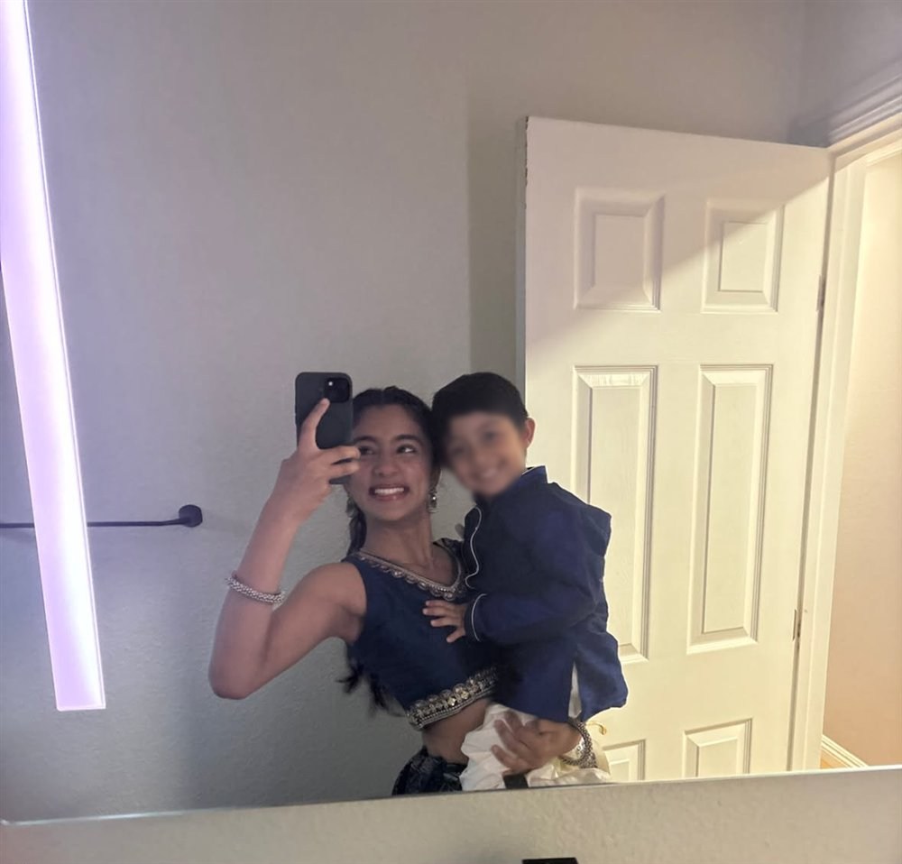 Neti in a blue outfit holding her smiling little cousin