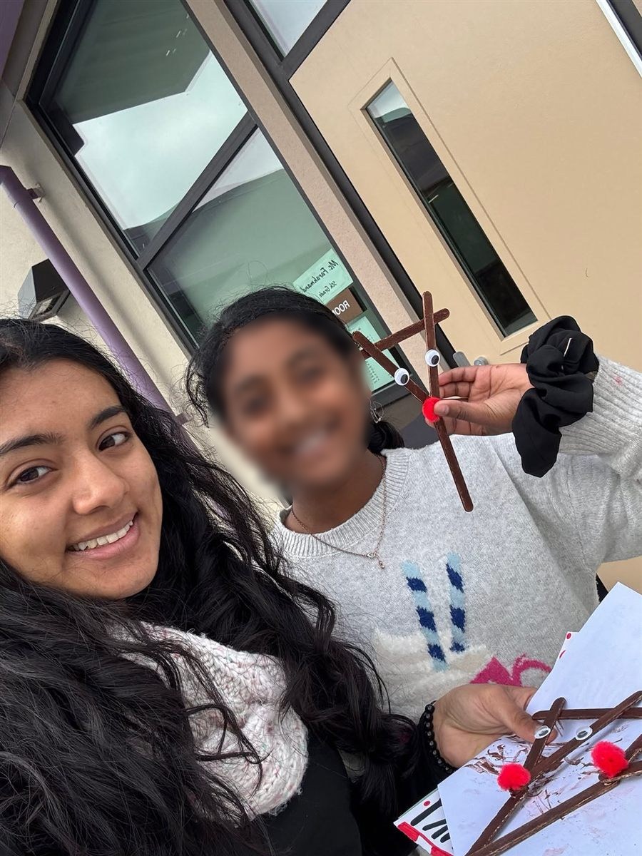 Neti with a mentee holding a handmade reindeer craft