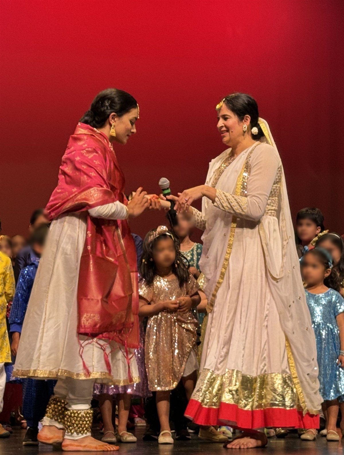 Neti receiving her degree from her Kathak guru, Ms. Vaishnaviji, on a stage against a red backdrop