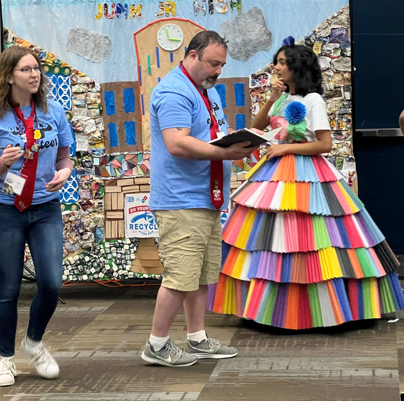 Neti in a hand-built layered rainbow paper dress at Globals in Kansas City, talking with a volunteer