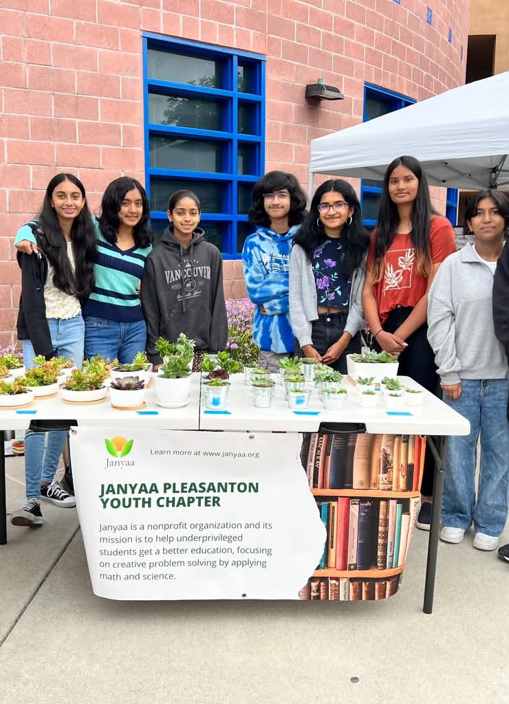 Janyaa Pleasanton Youth Chapter volunteers behind their succulent sale table and banner