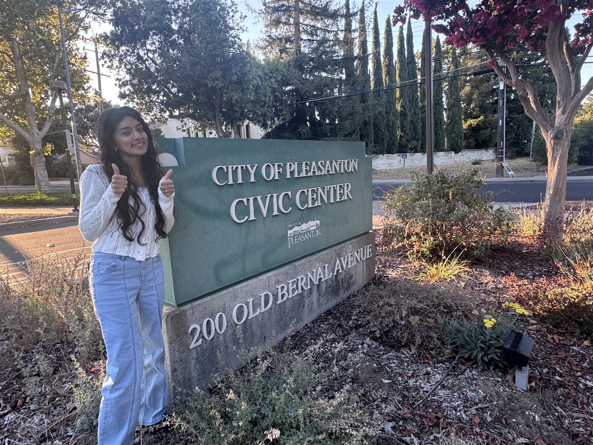 Neti next to the City of Pleasanton Civic Center sign