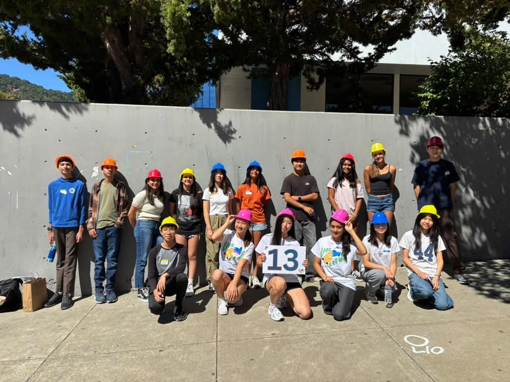 A group of Link Crew leaders in colorful hard hats holding a number 13 sign